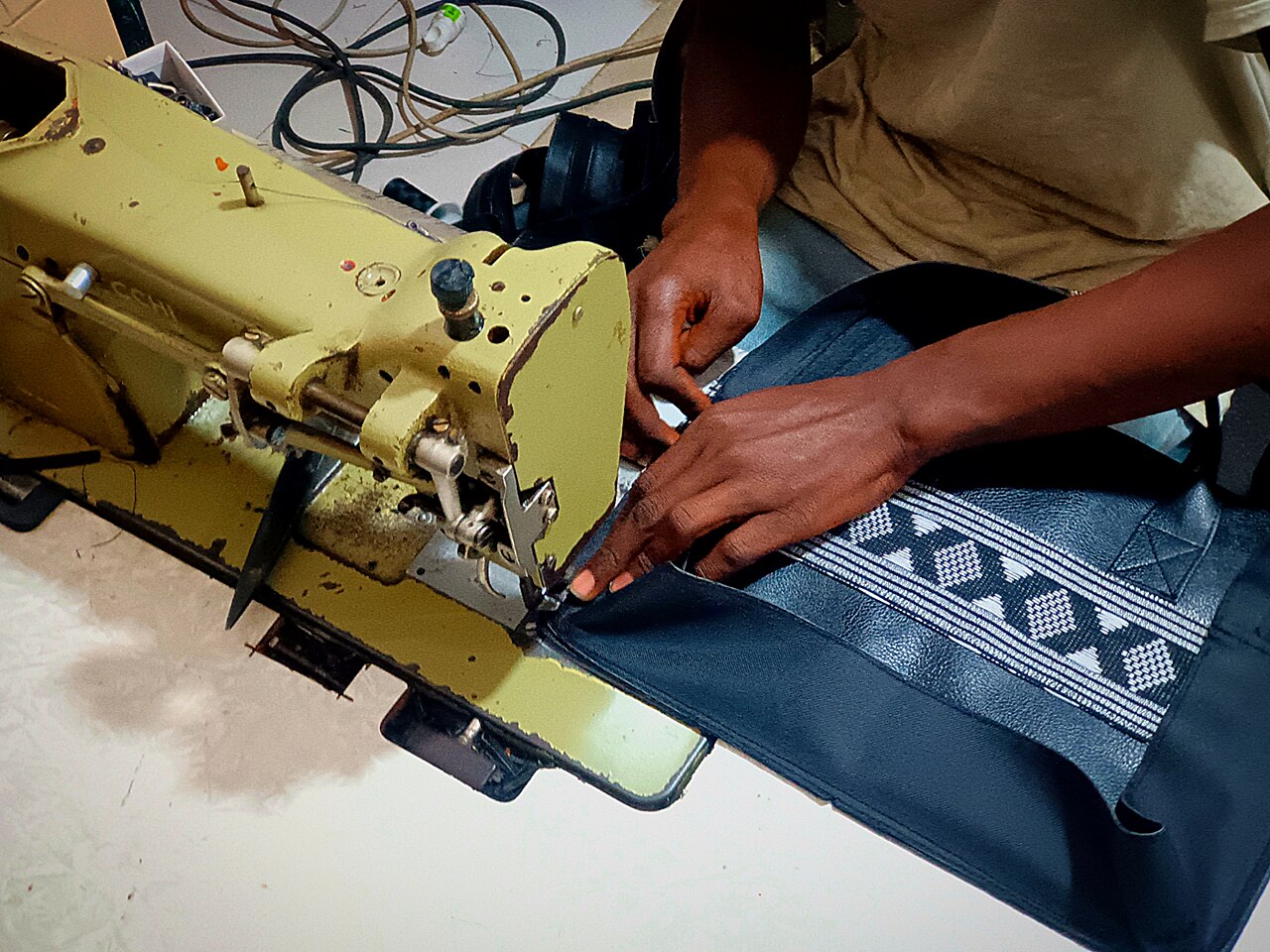 A tailor sewing a leather bag.